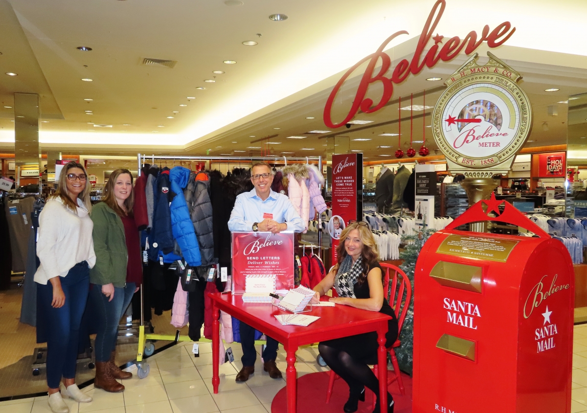 United Way and Macy’s Kingston Collections staff gather in front of some of the coats from Macy’s