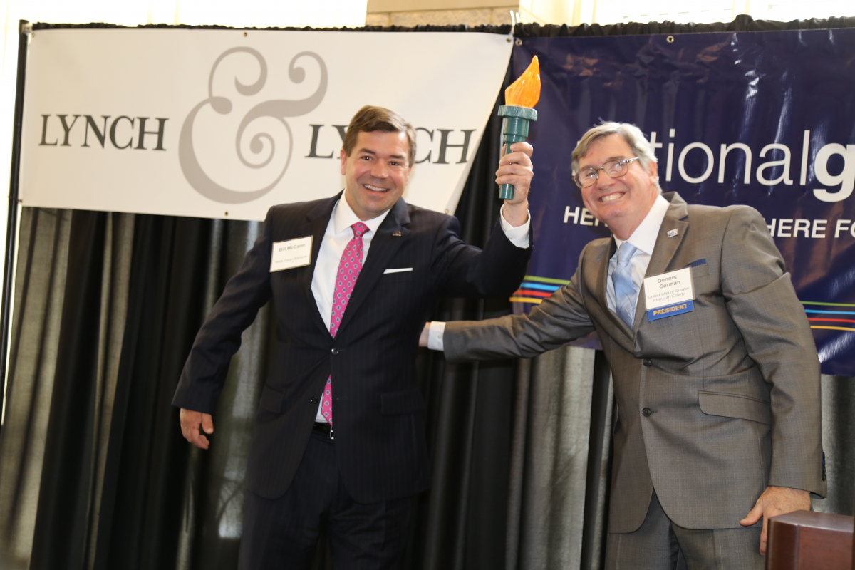 Bill McCann, First Vice President – Investment Officer and Branch Manager at Wells Fargo Advisors (left) receives  the campaign torch at United Way’s 96th Annual Meeting in June from Dennis Carman, President & CEO at United Way of Greater Plymouth County (right). 